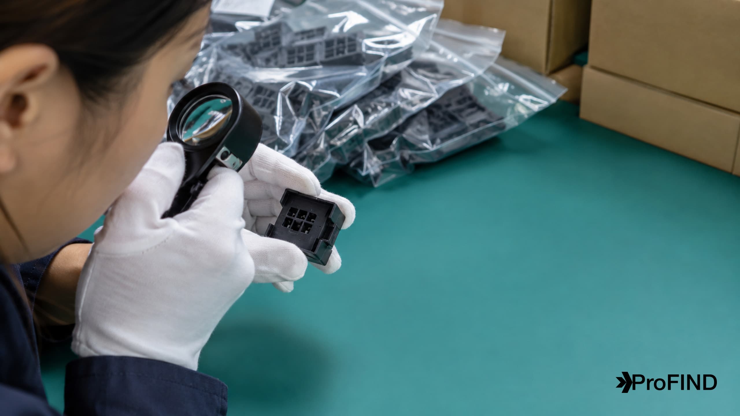 Gloved hands inspecting a connector beside sealed component bags at a receiving bench