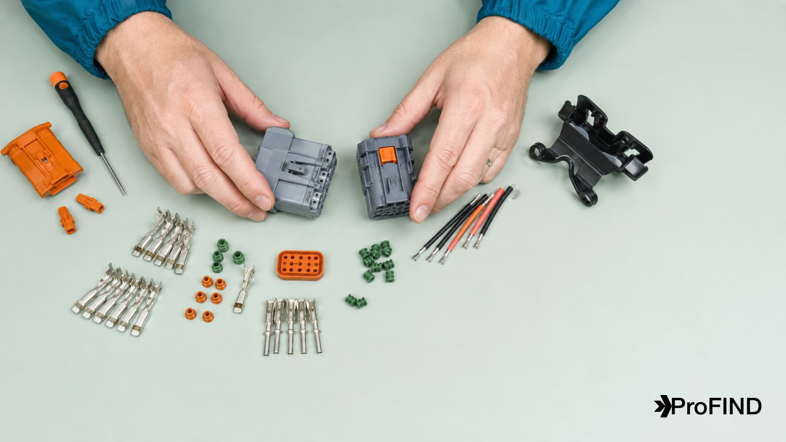 Hands organizing housings, contacts, seals, locks, and wires into a connector assembly