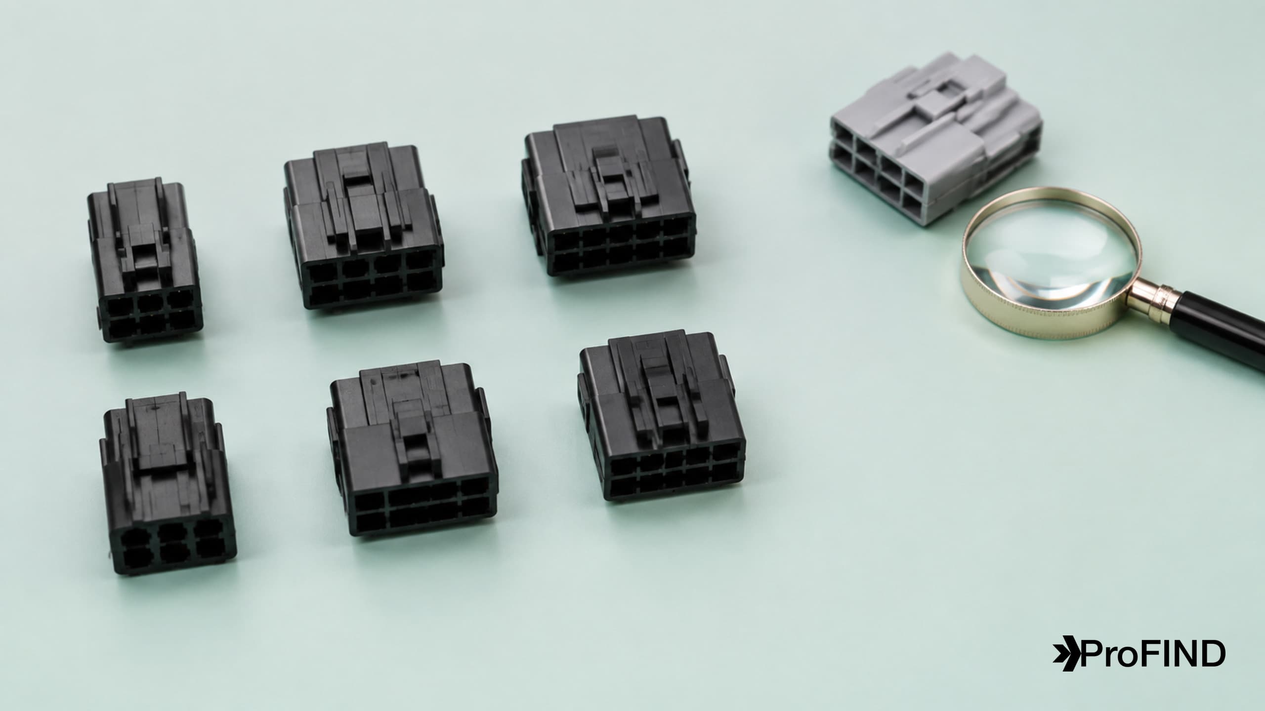 Similar-looking connector housings with different cavities and latches beside a magnifier