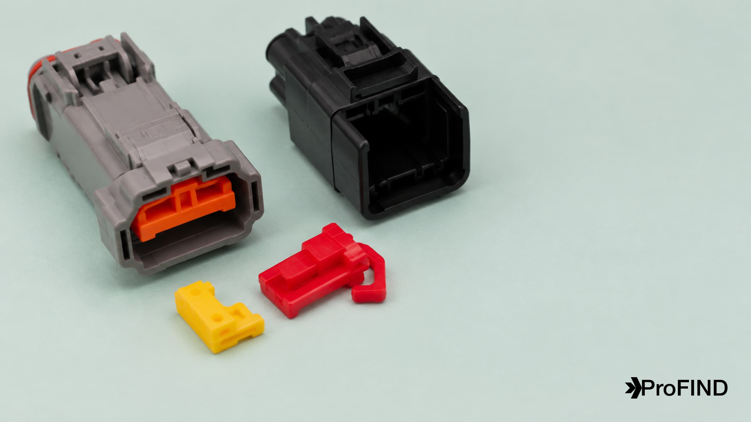 Orange, red, and yellow connector secondary locking components beside gray and black housings